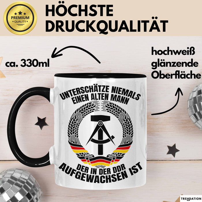 DDR Mann Tasse Geschenk Unterschätze Niemals Einen Alten Mann Der In Der DDR AufgewachsenIst Kaffee-Becher Schwarz Trendation